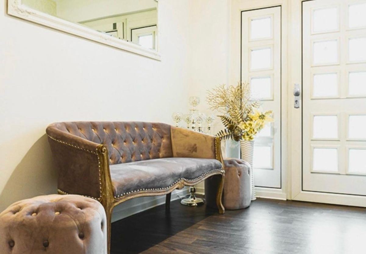Wartebereich der Beauty Lounge mit Samtsofa und Wandspiegel